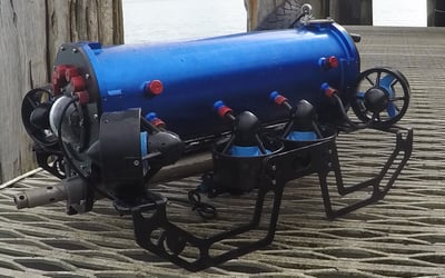 Custom blue underwater ROV with multiple thrusters on a timber deck.